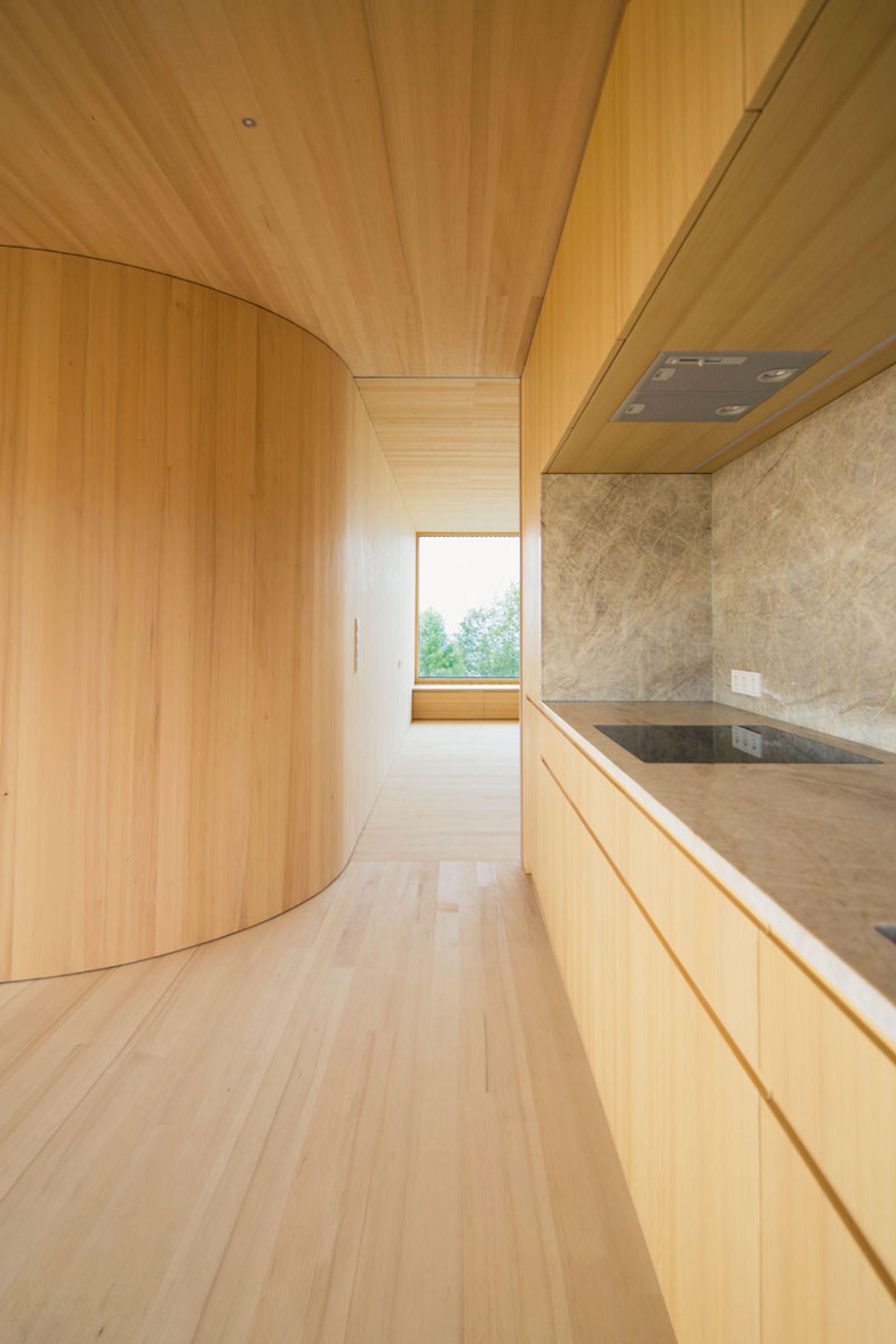 Blick an
der Küchenzeile
vorbei ins
Wohnzimmer mit
raumgroßem
Panoramafenster (Foto: juri troy architects)