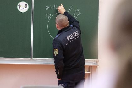 A police officer draws on the blackboard in front of pupils at an elementary school. To mark the international "Safer Internet Day", prevention officers educate children about the dangers of using digital media