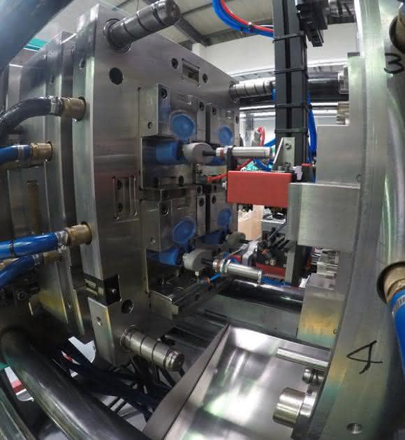 Weil die Verschlussmechanismen spiegelverkehrt aufgebaut sind, muss der Greifer die unteren zwei Kappen während der Zufuhr um 180 Grad drehen.