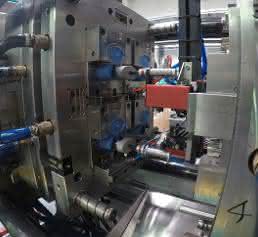 Because the closing mechanisms are mirror-inverted, the gripper must rotate the two lower caps by 180 degrees during feeding.