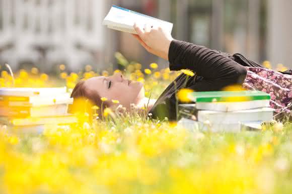 Junge Frau mit Buch in der Sonne