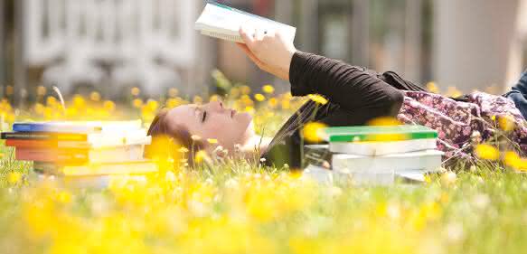 Junge Frau mit Buch in der Sonne