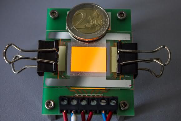 Orange leuchtende OLED auf einer Graphen-Elektrode. Die Zwei-Euro-Münze dient als Größenvergleich. (© Foto Fraunhofer FEP)