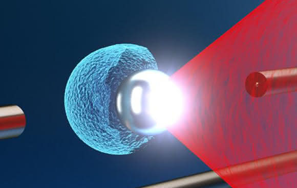 Der Texas Petawatt Laser Puls (rot) wird auf eine schwebende Mikrokugel fokussiert. Die enorme Lichtintensität verursacht die Explosion der Mikrokugel, wodurch potenziell vielseitig nutzbare energetische Ionen (blau) aus einer sehr kleinen Quelle erzeugt werden können. (Bild: Tobias Ostermayr)