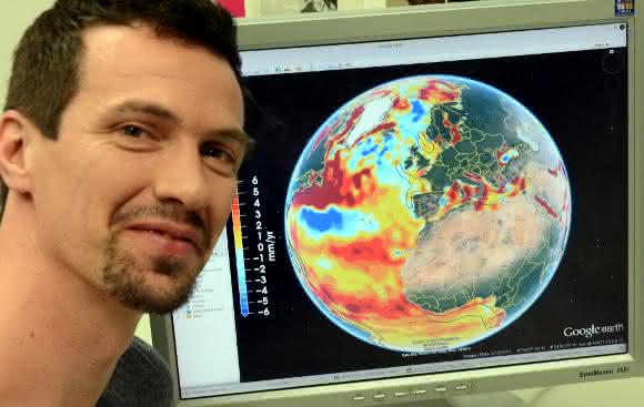 Dr.-Ing. Roelof Rietbroek vom Institut für Geodäsie und Geoinformation der Universität Bonn mit einer globalen Darstellung des Meeresspiegelanstiegs am Computer-Bildschirm. Die verschiedenen Farben bedeuten unterschiedliche Niveaus. (© Foto: Johannes Seiler / Uni Bonn)