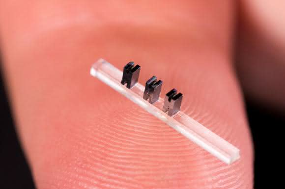 Drei Miniatur-Beschleunigermodule aus Silizium auf einem durchsichtigen Träger. (Bild: SLAC National Accelerator Laboratory)