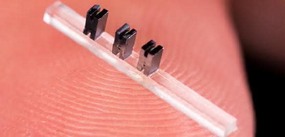 Drei Miniatur-Beschleunigermodule aus Silizium auf einem durchsichtigen Träger. (Bild: SLAC National Accelerator Laboratory)