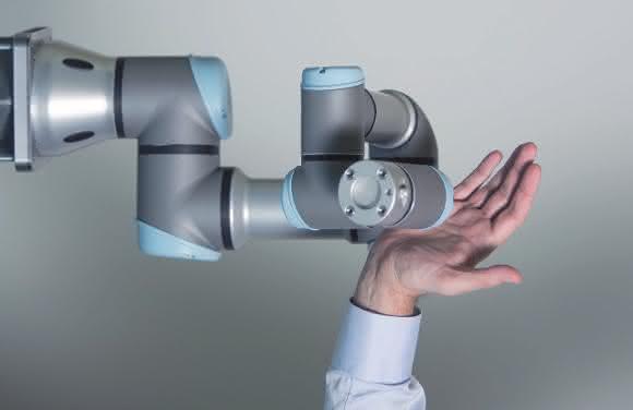 Roboterarm von Universal Robots mit menschlicher Hand Roboterarm von Universal Robots mit menschlicher Hand