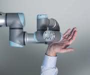 Roboterarm von Universal Robots mit menschlicher Hand Roboterarm von Universal Robots mit menschlicher Hand