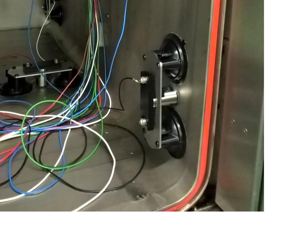Teil des Messaufbaus für eine Schallemissionsprüfung: Wand einer Sterilisierkammer mit Kabeldurchführungen und Schallemissionssensoren in Vakuumhaltern. Teil des Messaufbaus für eine Schallemissionsprüfung: Wand einer Sterilisierkammer mit Kabeldurchführungen und Schallemissionssensoren in Vakuumhaltern.