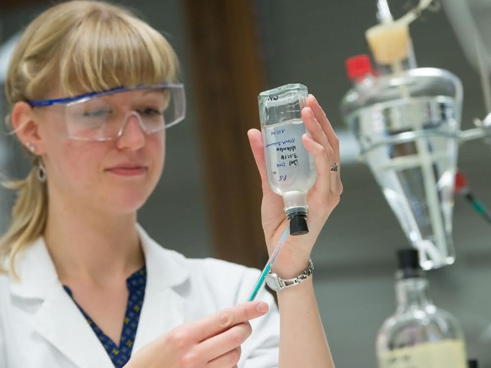 Eine biologisch-technische Assistentin, entnimmt der anaeroben Bakterienkultur eine Probe.