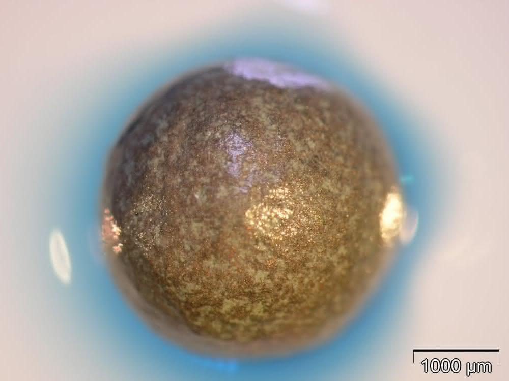 Metallische Hohlkugel mit Pilzenzymen. Die Enzymreaktion (blaue Corona) ist mit einem Farbstoff sichtbar gemacht.