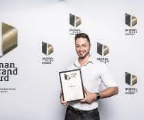 Dominic Fischer, Eventmarketing Manager bei Dematic, nahm in Berlin den German Brand Award für Dematic entgegen.