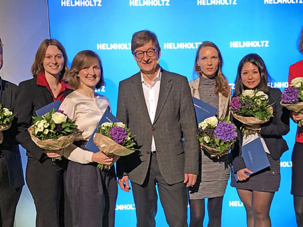 Foto von der Preisverleihung: Links und rechts vom Helmholtz-Präsidenten stehen jeweils drei Preisträger. Jeder Preisträger hält einen Blumenstrauß und eine blaue Mappe in den Händen.