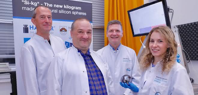 Die Preisträger (von links nach rechts): Dr.-Ing. Rudolf Meeß, Thomas Wiedenhöfer, Prof. Dr. Frank Härtig und Katharina Lehrmann. Foto der Preisträger, die Preisträgerin hält eine Siliziumkugel in der (behandschuhten) Hand.