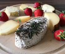 Verschiedene Käsesorten und Erdbeeren auf einem Holzbrett