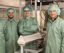 Vier Wissenschaftler in grünen Kitteln und mit grünen Haarnetzen