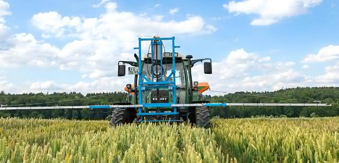 Nährstoff- und Düngebedarf ermitteln und optimieren: Algorithmen und Sensoren für nachhaltige Landwirtschaft Traktor mit Düngevorrichtung auf einem Getreidefeld