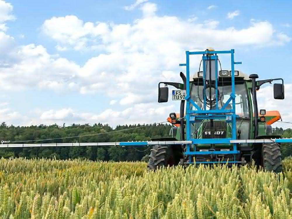 Nährstoff- und Düngebedarf ermitteln und optimieren: Algorithmen und Sensoren für nachhaltige Landwirtschaft Traktor mit Düngevorrichtung auf einem Getreidefeld