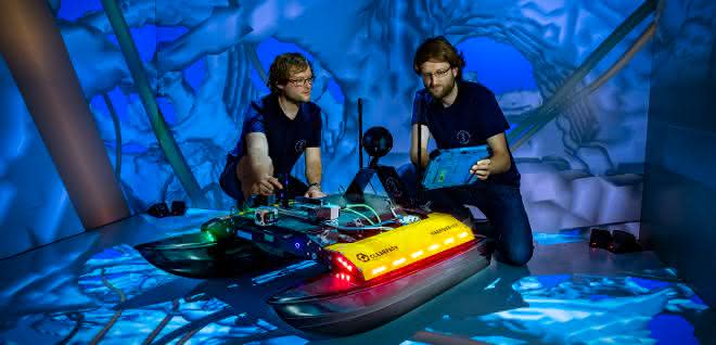 Zwei Freiberger Informatiker an dem neu entwickelten Schwimmroboter „Elisabeth“ in der CAVE. Zwei Freiberger Informatiker an dem neu entwickelten Schwimmroboter „Elisabeth“ in der CAVE.