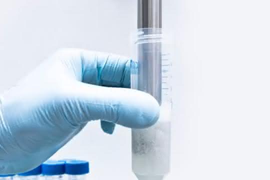 Hand hält Behälter mit Probe beim Dispergiervorgang
