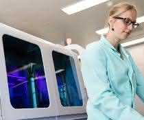 Labormitarbeiterin bei der Arbeit, dahinter ein Cobas-System