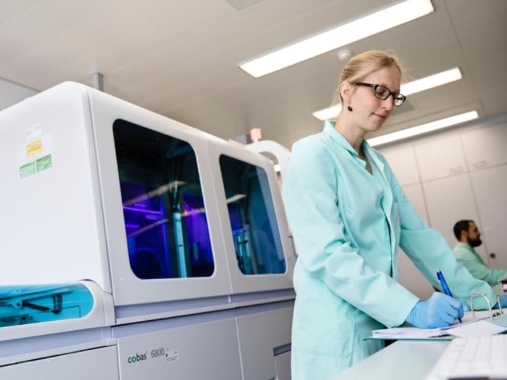 In-vitro Diagnostik: SARS-CoV-2-Test mit vollautomatischen Systemen Labormitarbeiterin bei der Arbeit, dahinter ein Cobas-System