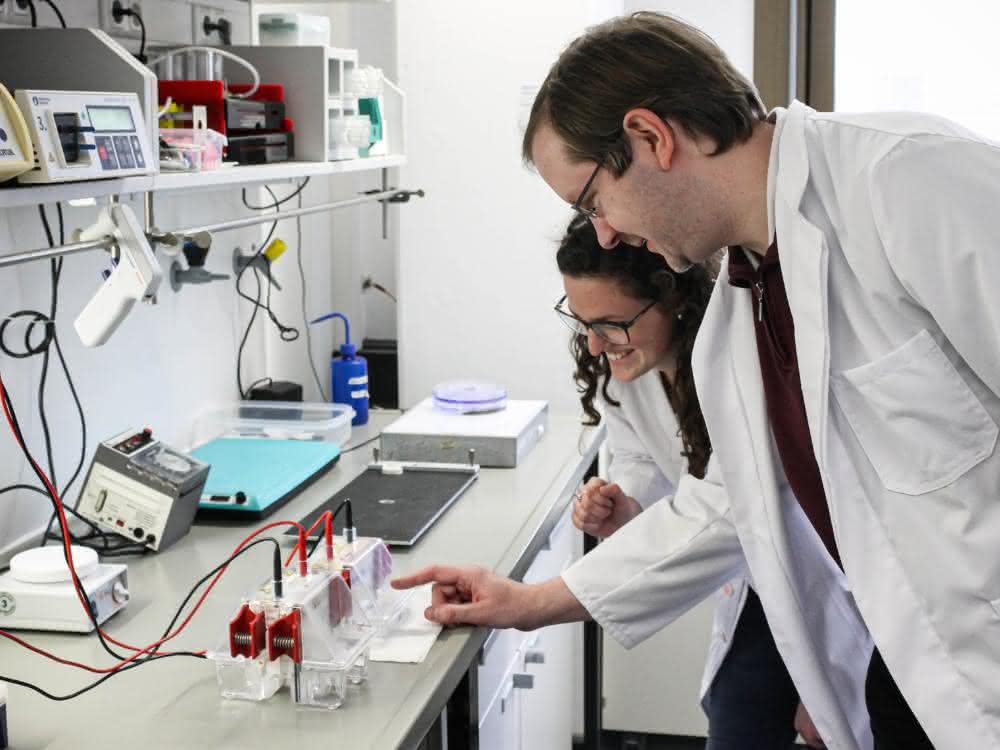 Clarissa Lanzloth B.Sc. und Dr. Frank Mickoleit in einem Labor der Bayreuther Mikrobiologie. Die Elektrophorese-Apparatur dient der Auftrennung und Analyse von Proteinen. Clarissa Lanzloth B.Sc. und Dr. Frank Mickoleit im Labor