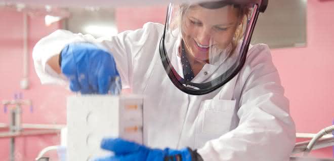 Biobanken sammeln, lagern und verarbeiten qualitätsgesichert und datenschutzkonform humane Bioproben wie Blut oder Gewebe, die sie der Forschung bereitstellen. Labormitarbeiterin mit Gesichtsschutz und blauen Handschuhen hält Probenbehältnis