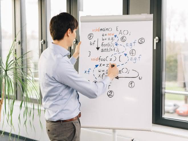 Junger Mann vor Flip Chart mit Formeln