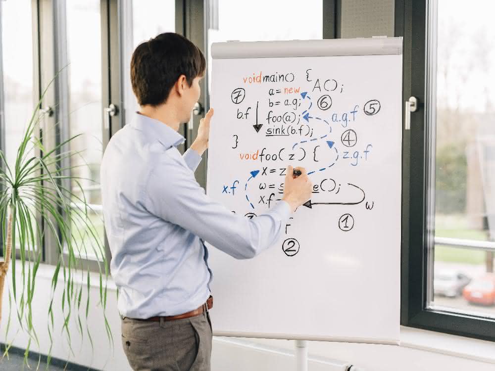 Junger Mann vor Flip Chart mit Formeln