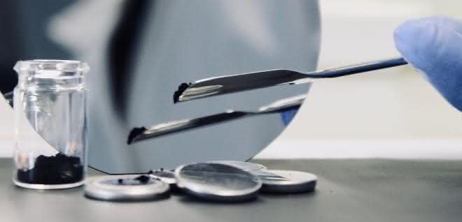 Mit neuen Materialien möchten die Forschenden sichere und langlebige Hochleistungszellen möglich machen. Schwarzes Pulver im Präparateglas und Knopfzellen