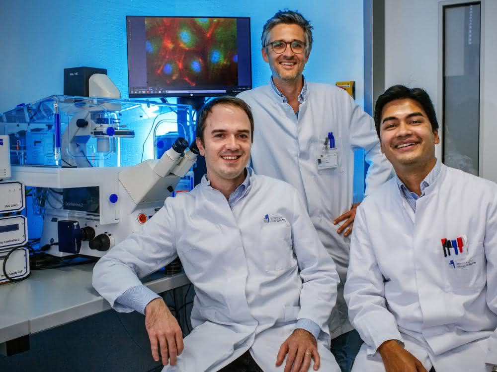 Andreas Zietzer (links), Felix Jansen (Mitte) und Rabiul Hosen (rechts) neben einem Fluoreszenzmikroskop mit großem Bildschirm in einem Forschungslabor des Uniklinikums Bonn. Andreas Zietzer, Felix Jansen und Rabiul Hosen neben einem Fluoreszenzmikroskop mit großem Bildschirm in einem Forschungslabor des Uniklinikums Bonn.