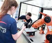 Roboterarm und programmierende Personen
