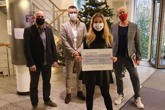Eva-Maria Büttner zeigt den Scheck. Dahinter im Bild: Dirk Waasen, Peter Eberhard und Matthäus Hose.
