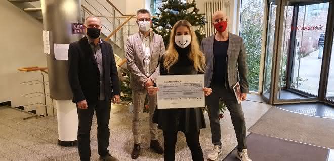 Eva-Maria Büttner zeigt den Scheck. Dahinter im Bild: Dirk Waasen, Peter Eberhard und Matthäus Hose.