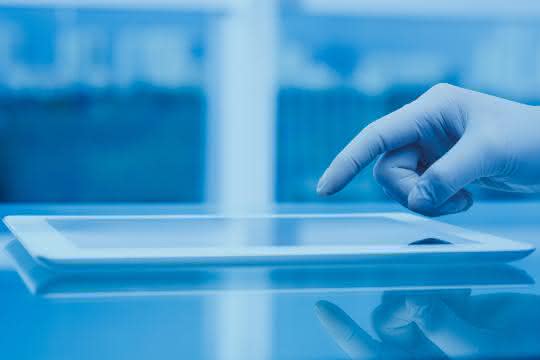 Hand (mit Laborhandschuh) bedient Tablet