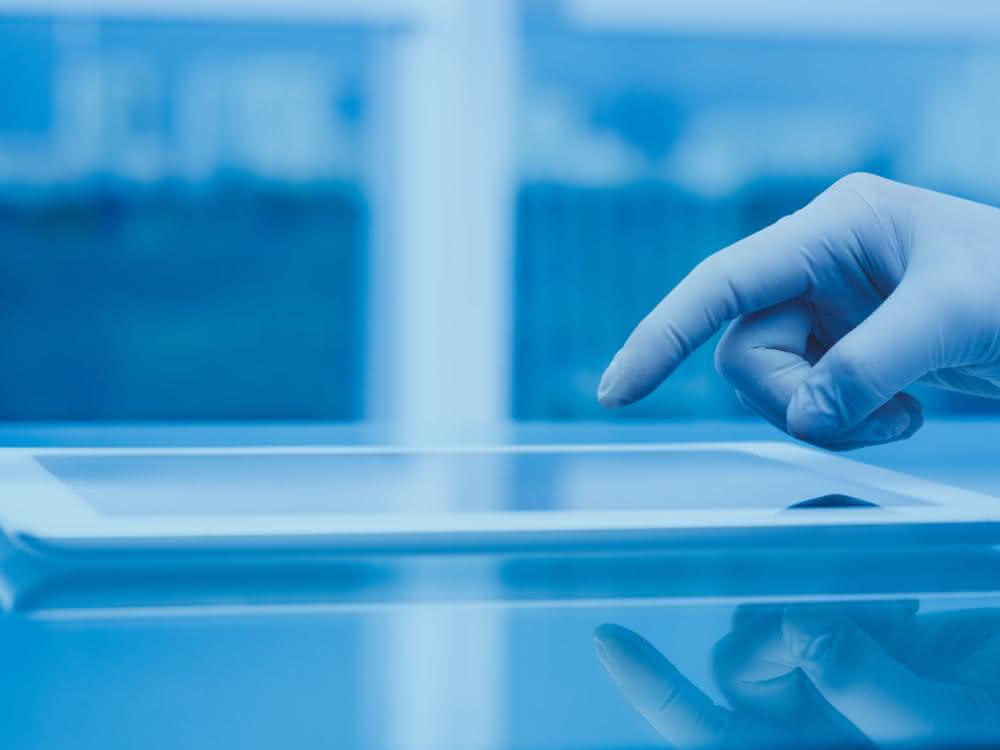 Hand (mit Laborhandschuh) bedient Tablet