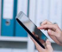 Frau am Tablet vor Regal mit Aktenordnern
