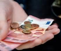 Euro-Scheine und -Münzen in der Hand Euro-Scheine und -Münzen in der Hand