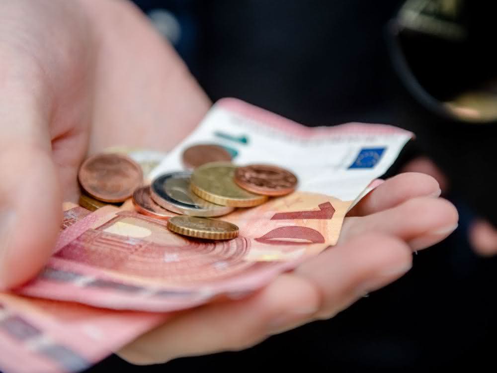Euro-Scheine und -Münzen in der Hand