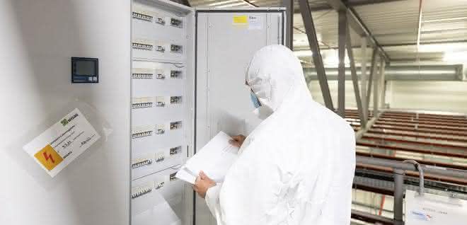 Unterverteilung Person in Reinraumkleidung am Verteilerschrank