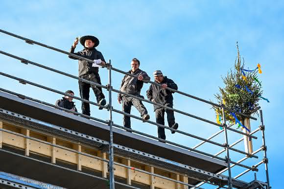 Handwerker stellten den traditionellen Baum anlässlich des Richtfests auf das Dach des Wohnbaus am Hammerweg.